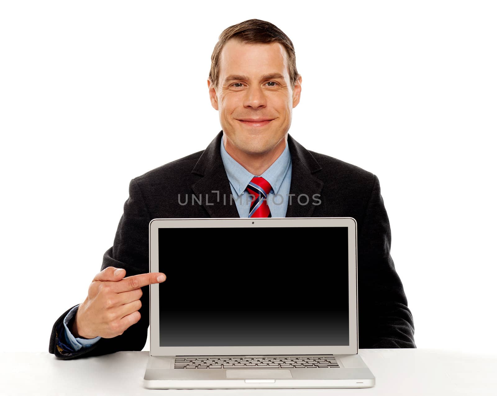 Seated young businessman pointing at blank laptop screen. Laptop facing camera