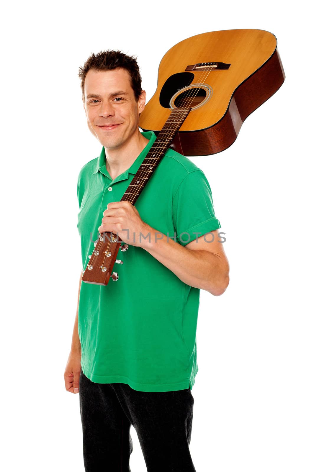 Cheerful handsome casual man with guitar on shoulders looking at camera