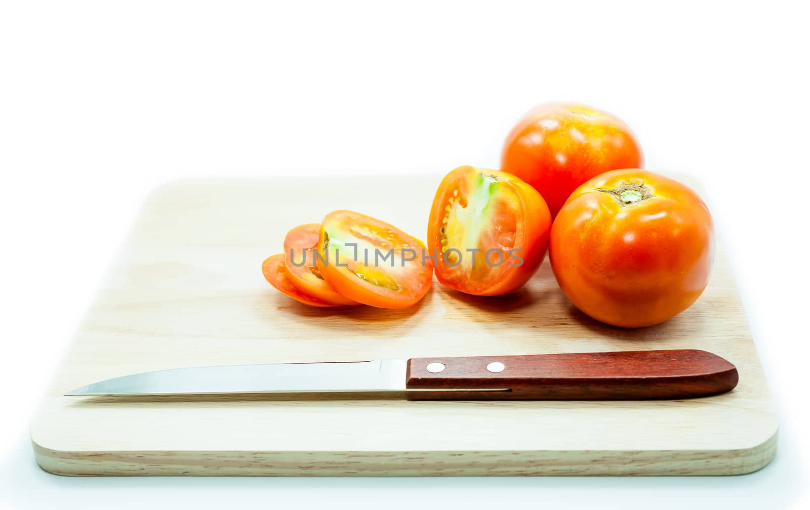 Tomato and knife on cutting board isolated on a white background