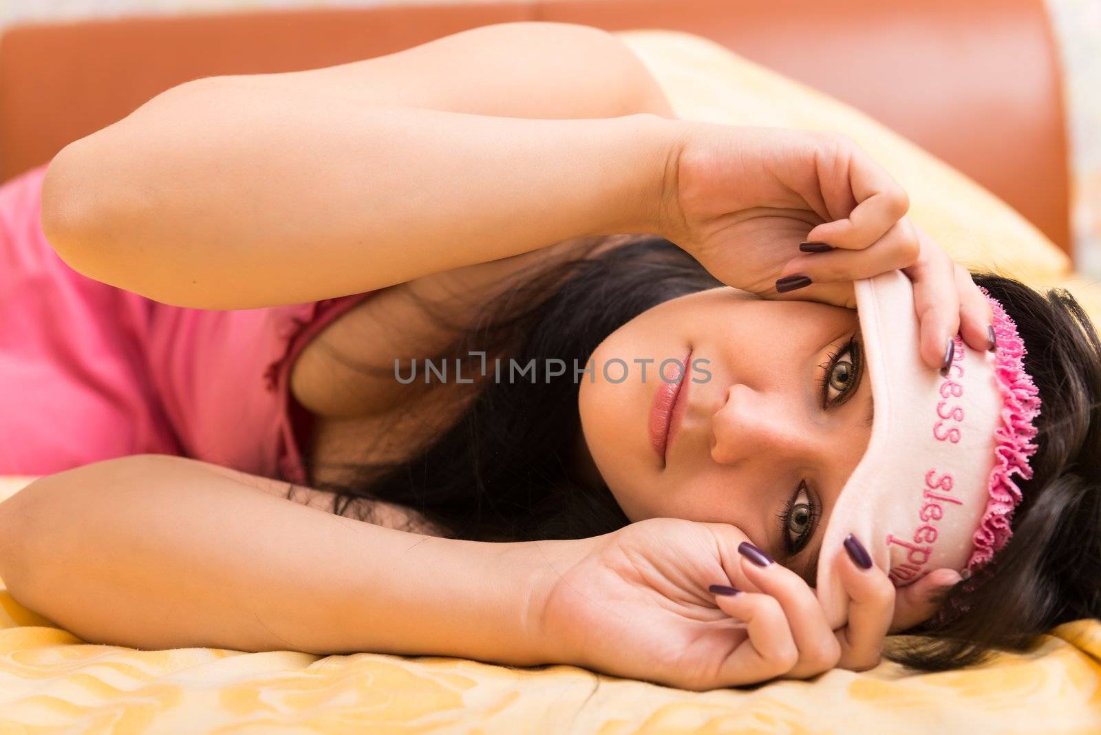 Young woman in sleep eye mask on yellow furnishing