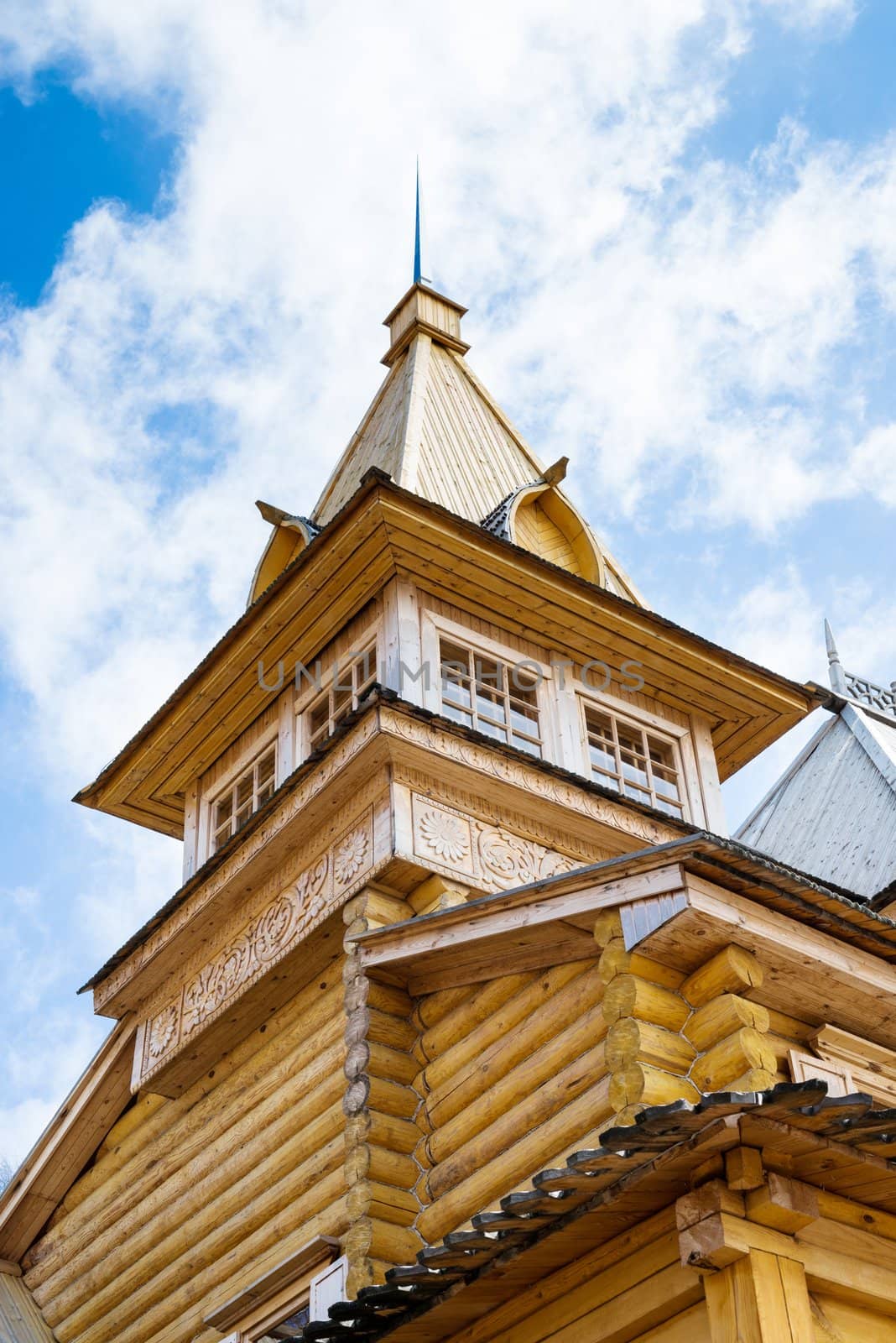 Wooden log house with blue cloudy sky above, Russian traditional architecture.
