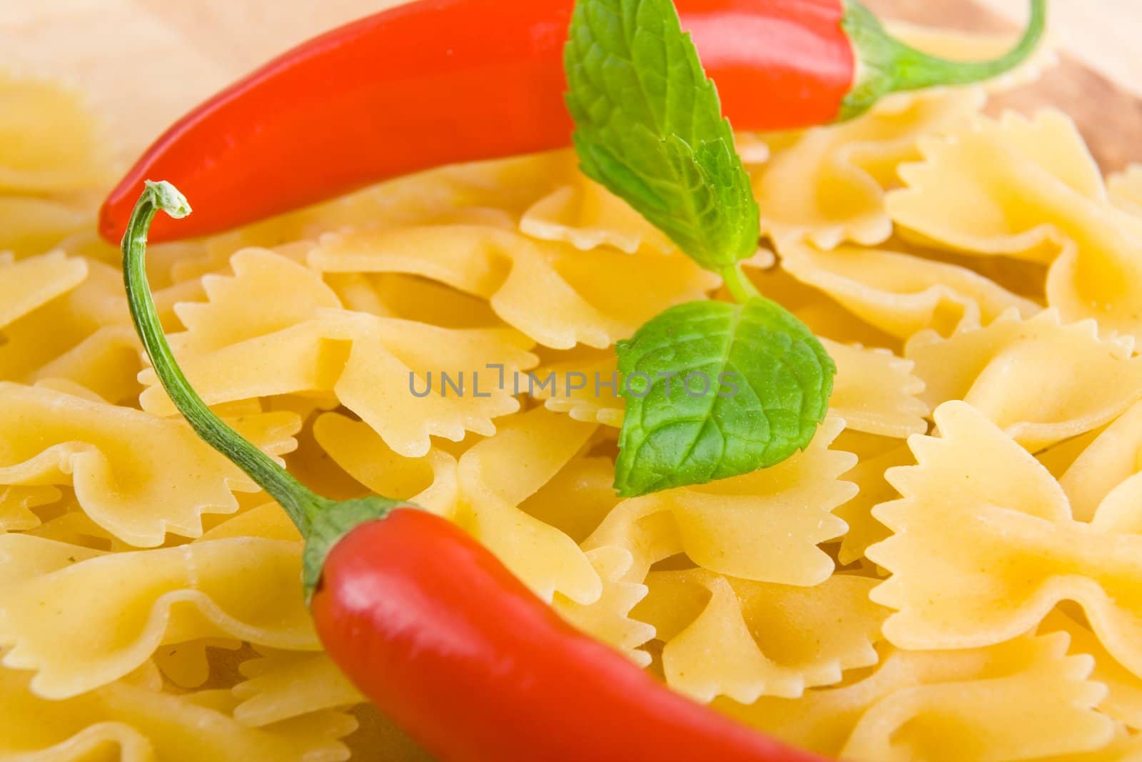 Golden raw dried Italian pasta with other ingredients on kitchen desk.