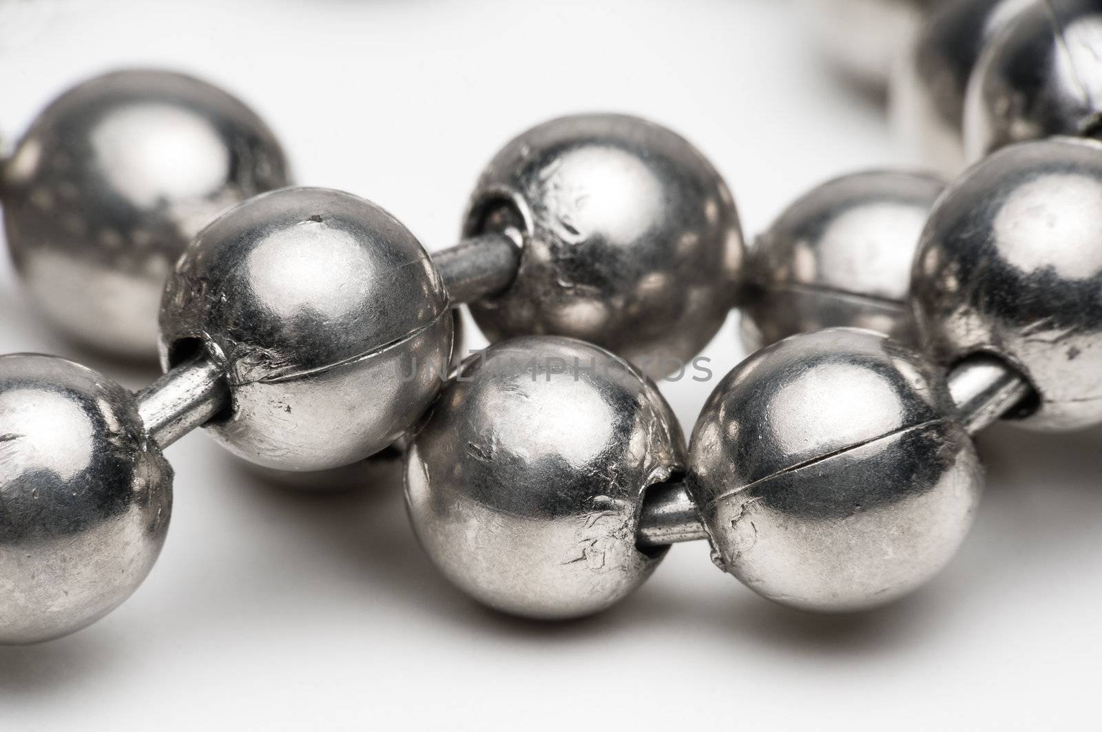 Macro shot of silver metal ball necklace on a white background.
