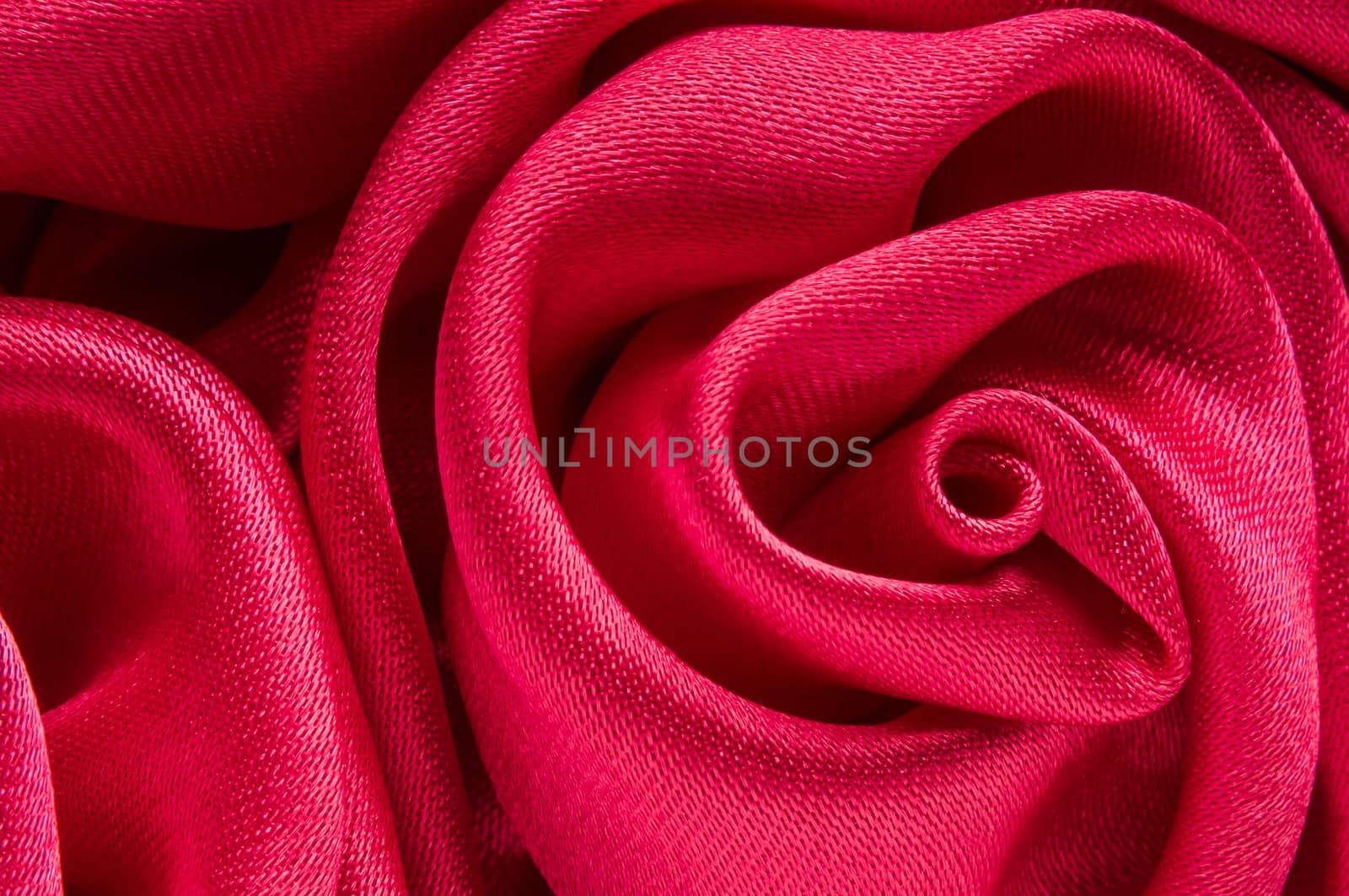 Close up of shiny red fabric rose shaped flower.