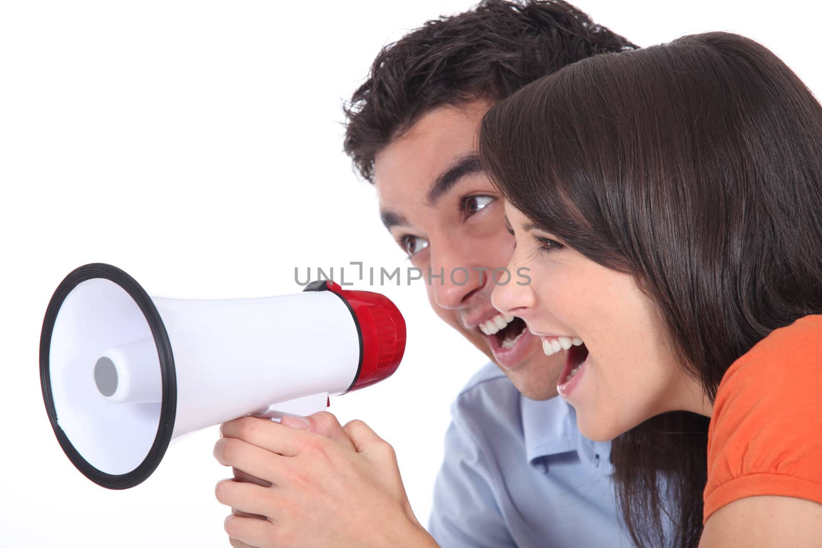 Young couple shouting into a megaphone by phovoir