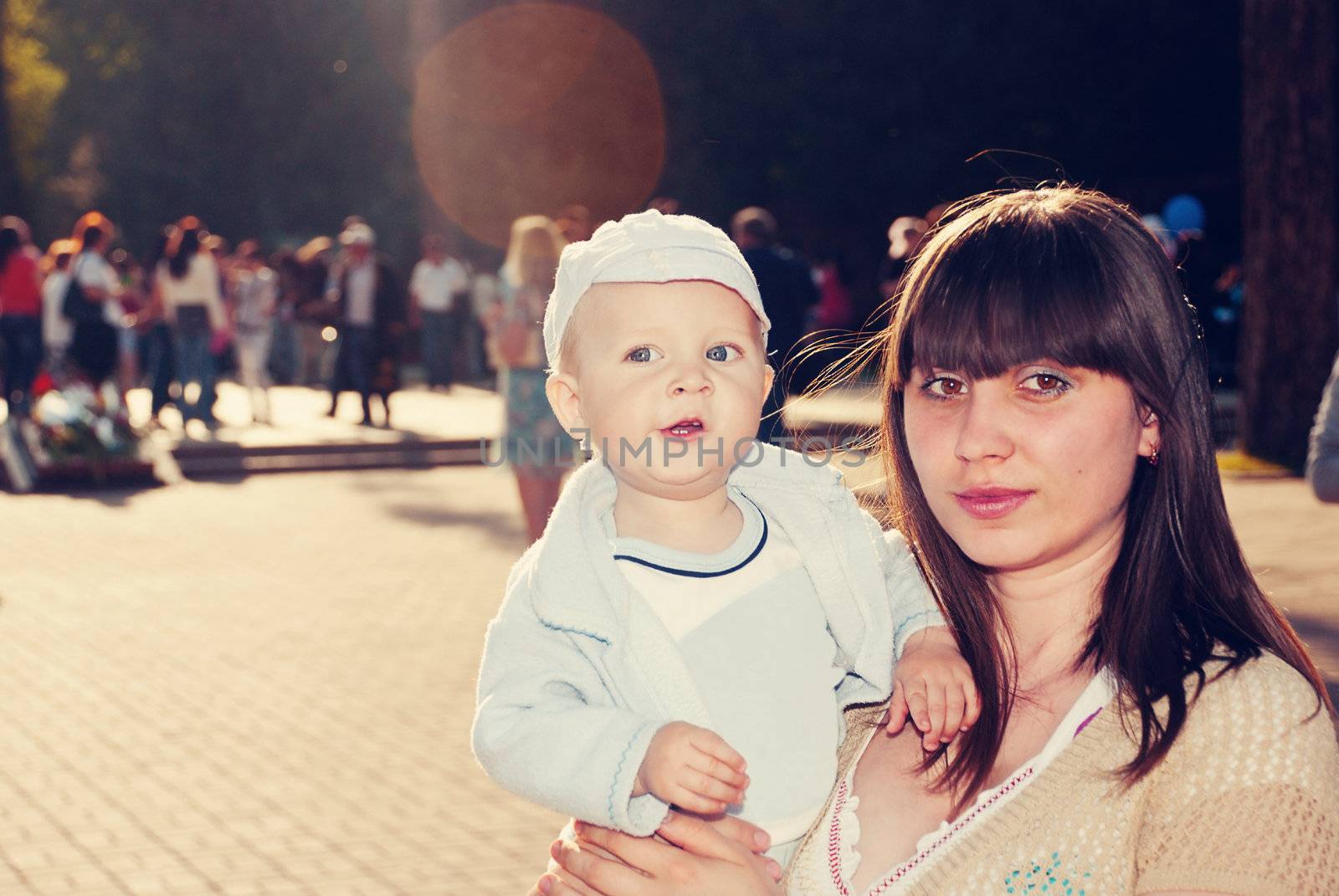 Young charming mother with her son in her arms for a walk in a park.