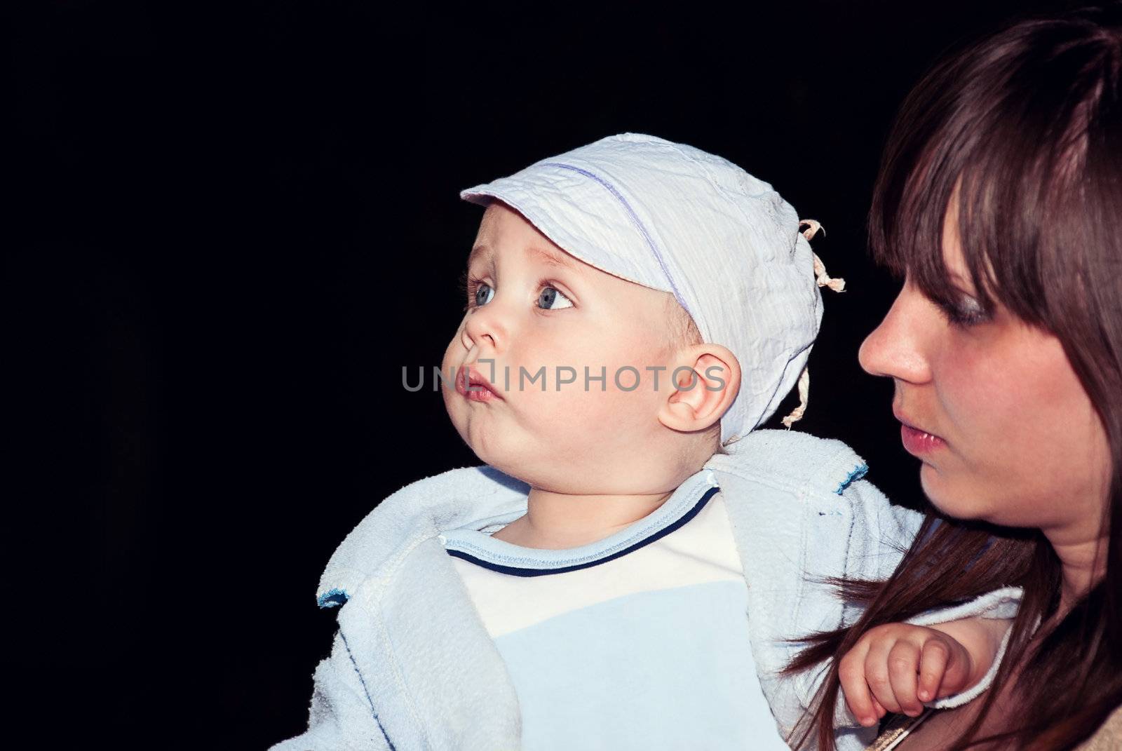 Mother and son in her arms to the side looking on a black background.