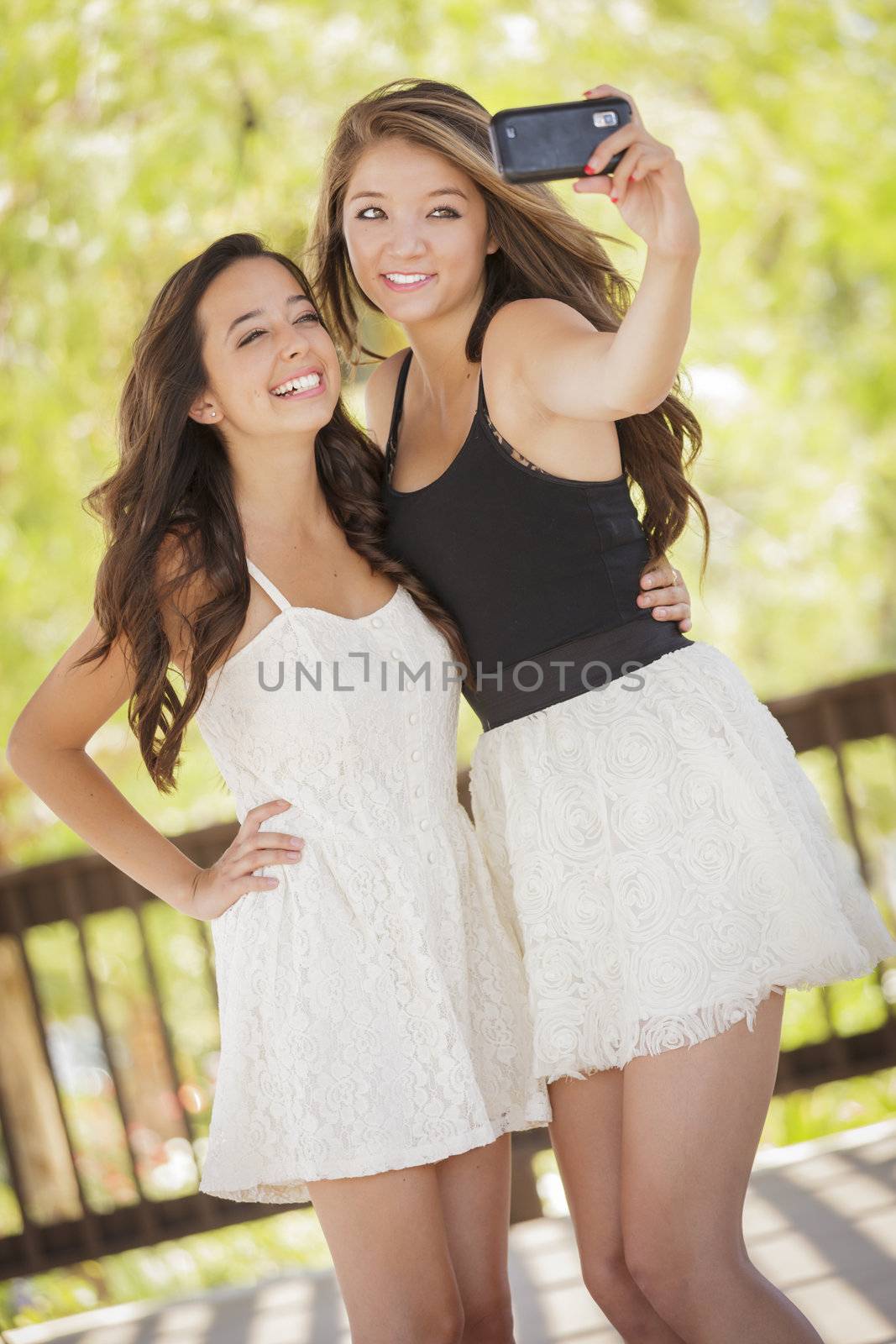 Two Attractive Mixed Race Girlfriends Taking Self Portrait with Their Phone Camera Outdoors.