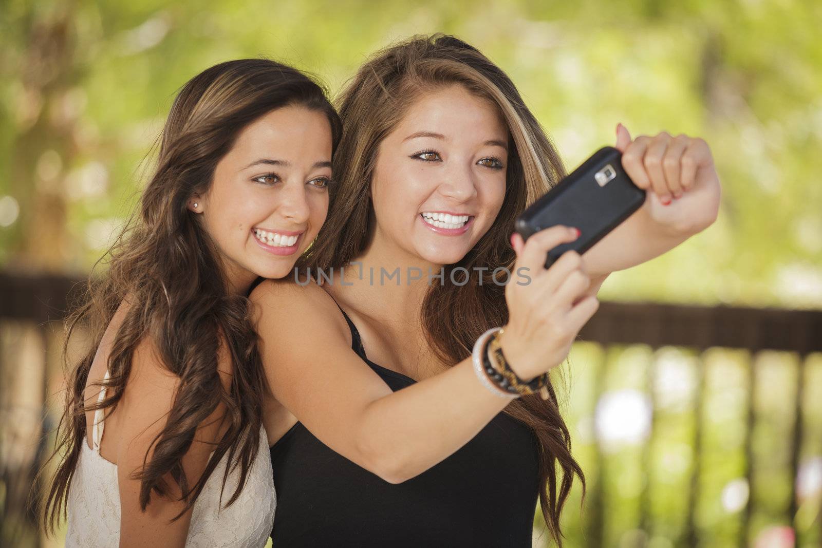 Two Attractive Mixed Race Girlfriends Taking Self Portrait with Their Phone Camera Outdoors.