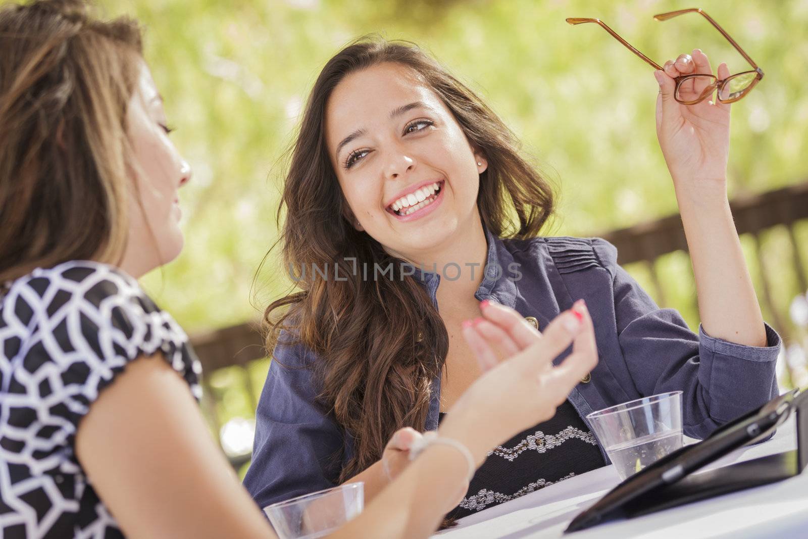 Attractive Mixed Race Girls Smiling and Talking While Working on Smart Mobile Phone and Tablet Computer.