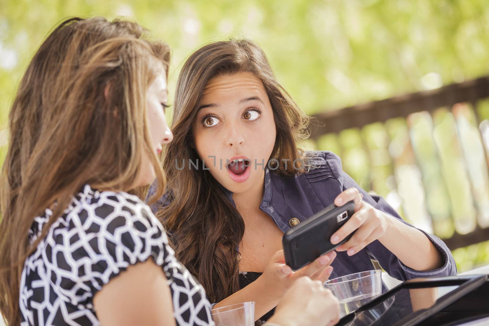Attractive Shocked Mixed Race Girls Working on Smart Mobile Phone and Tablet Computer.