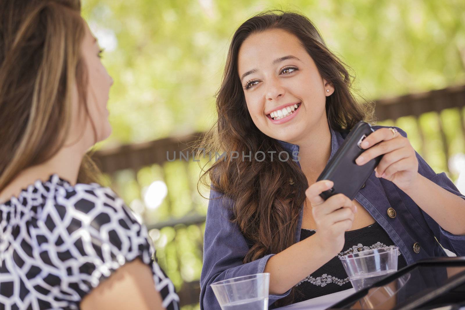 Attractive Mixed Race Girls Smiling and Talking While Working on Smart Mobile Phone and Tablet Computer.