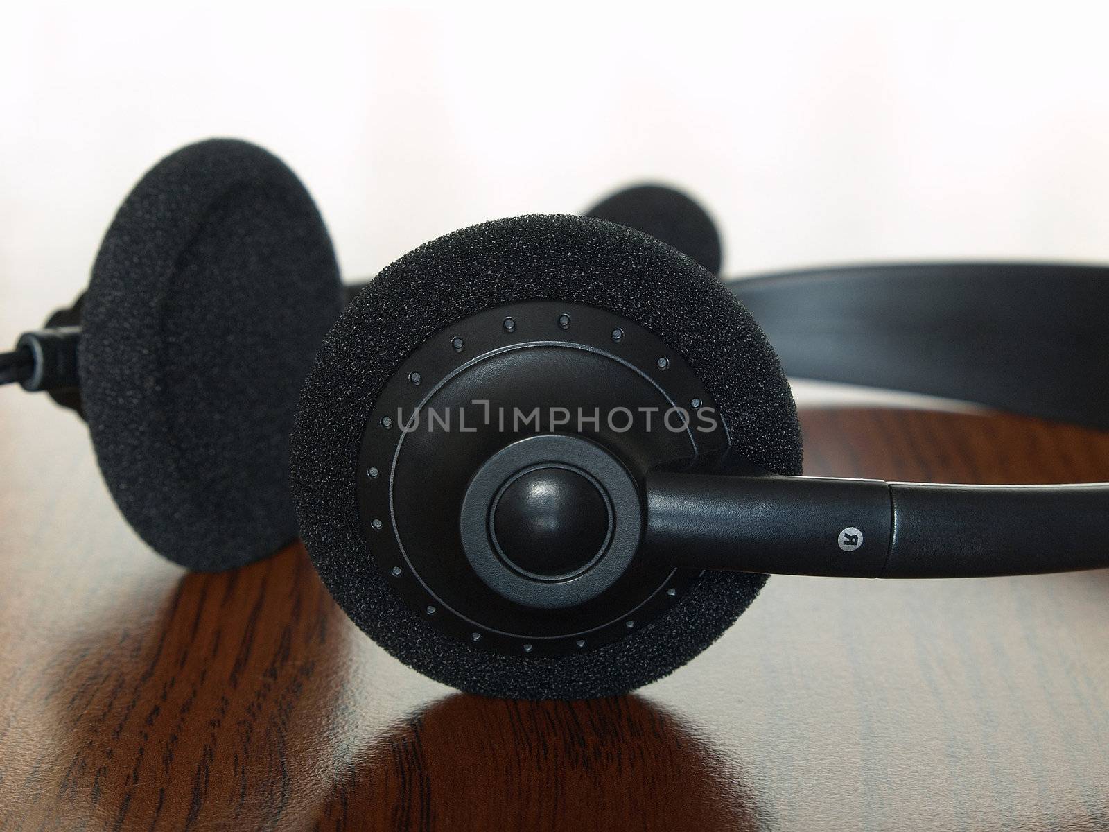 Black  headset on a wooden table taken closeup.