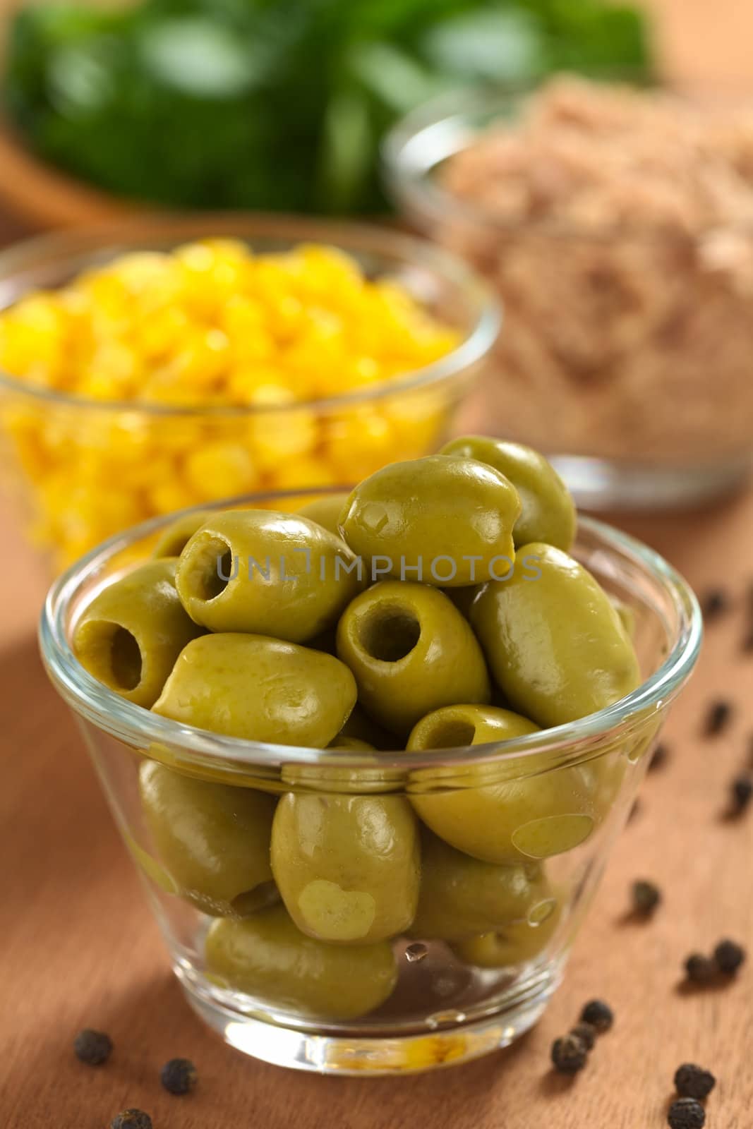 Preparing a fresh salad. Green olives with sweet corn, tuna and watercress (Selective Focus, Focus on the front of the olives on the top) 