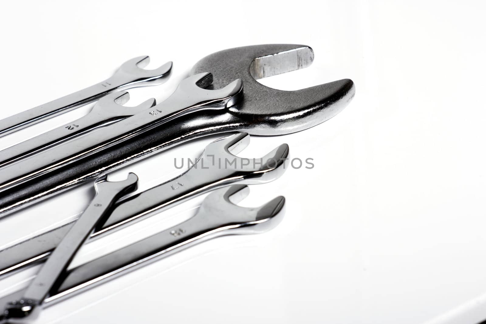 Some steel wrenches of different sizes on a white background