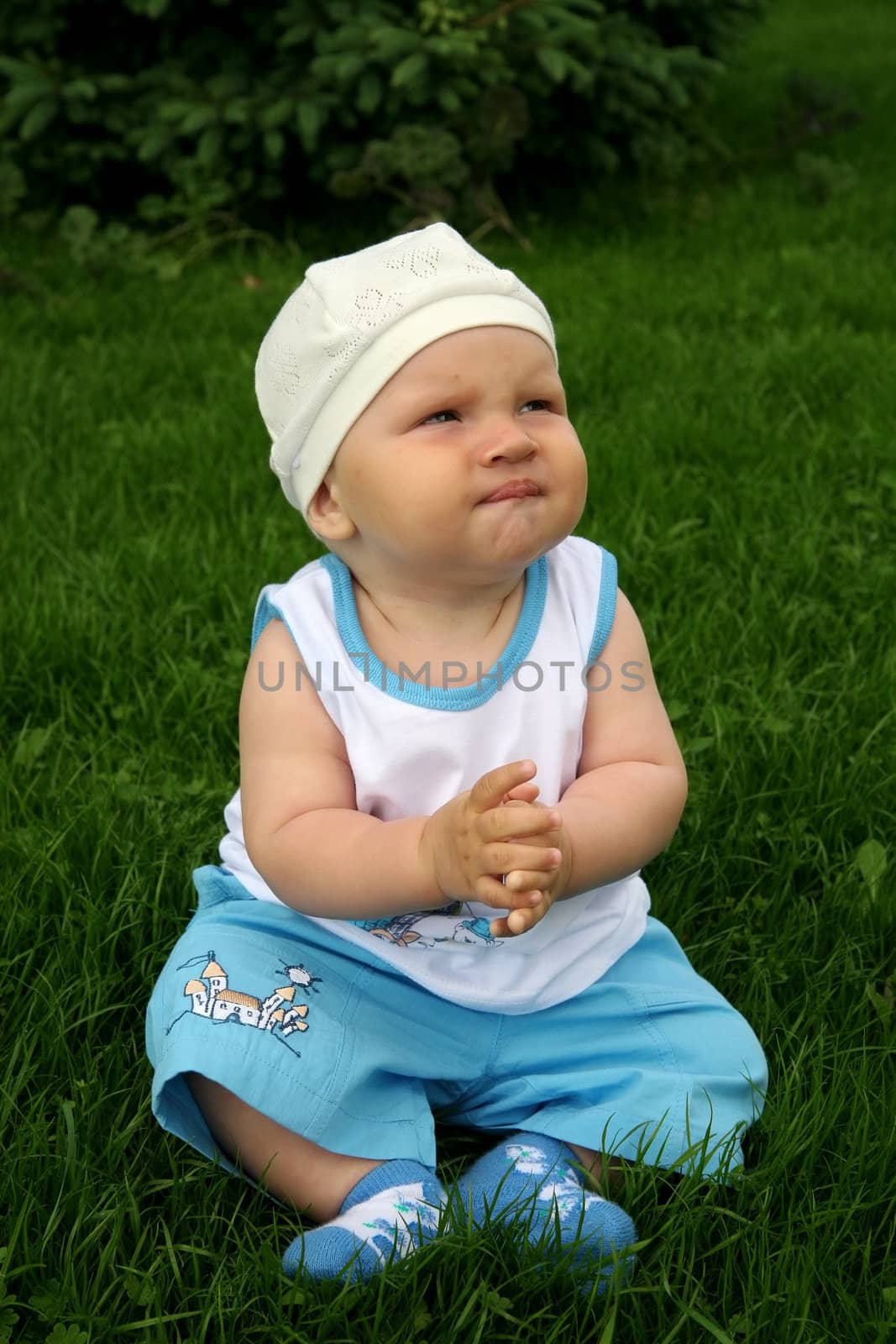 little boy with a happy kind sits on a grass