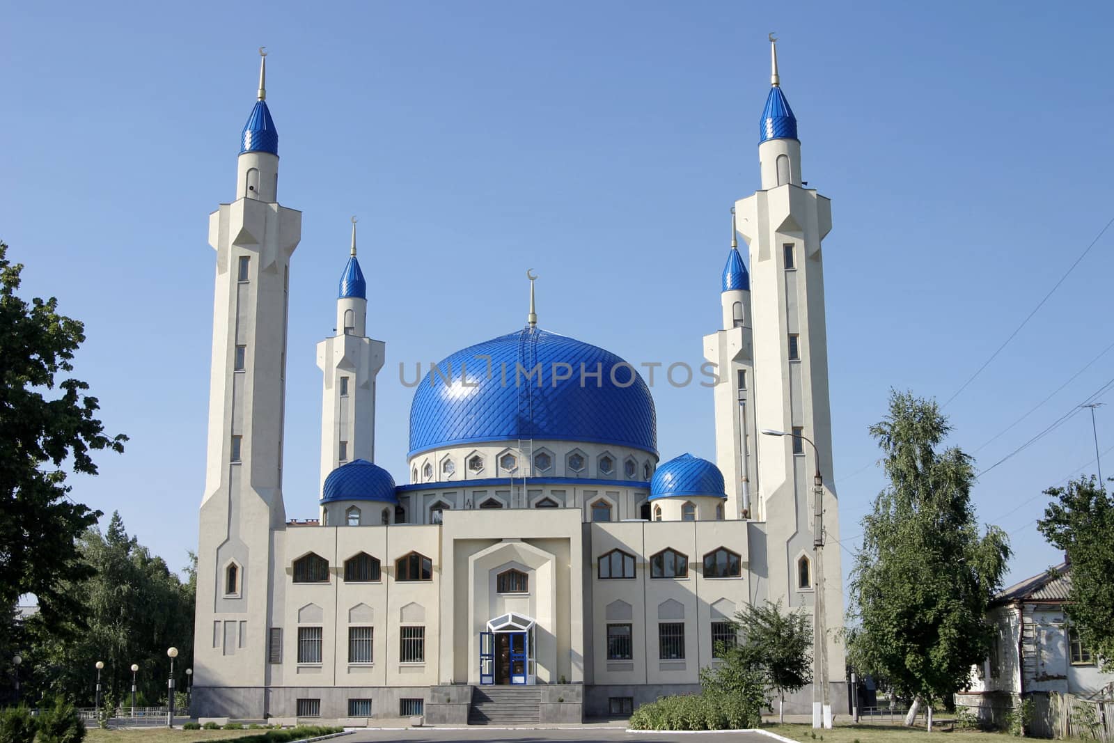 White mosque with blue domes against an unflawed sky