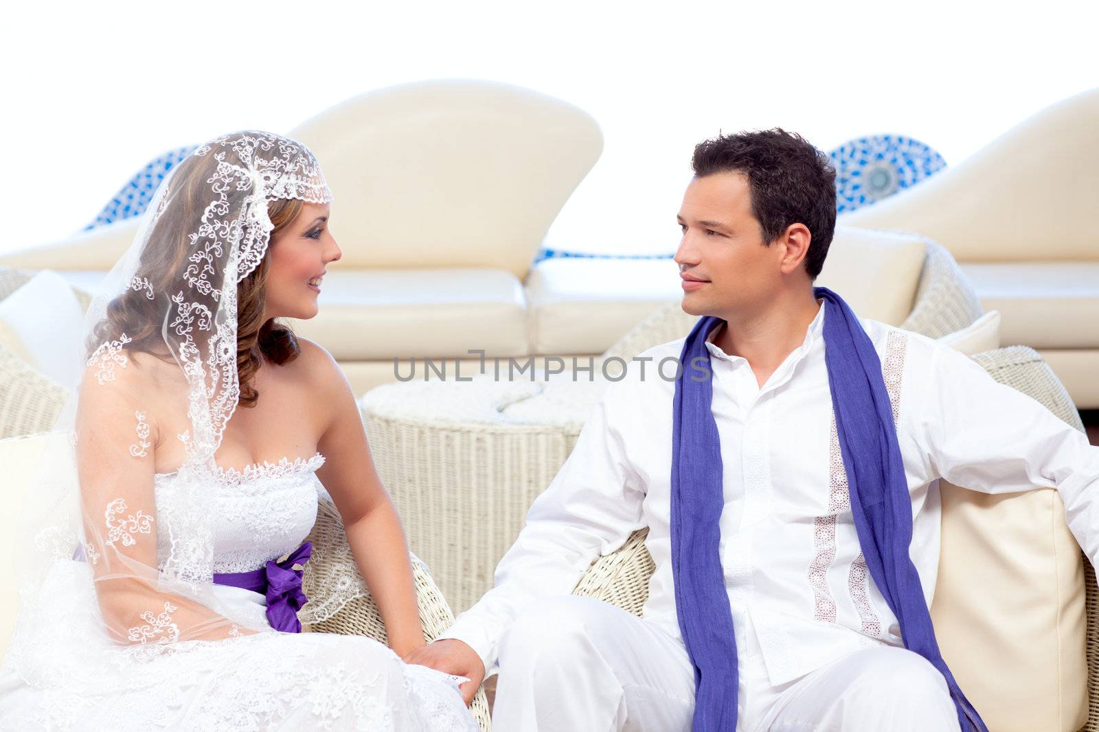 Couple in wedding day relaxed in white terrace couch outdoor