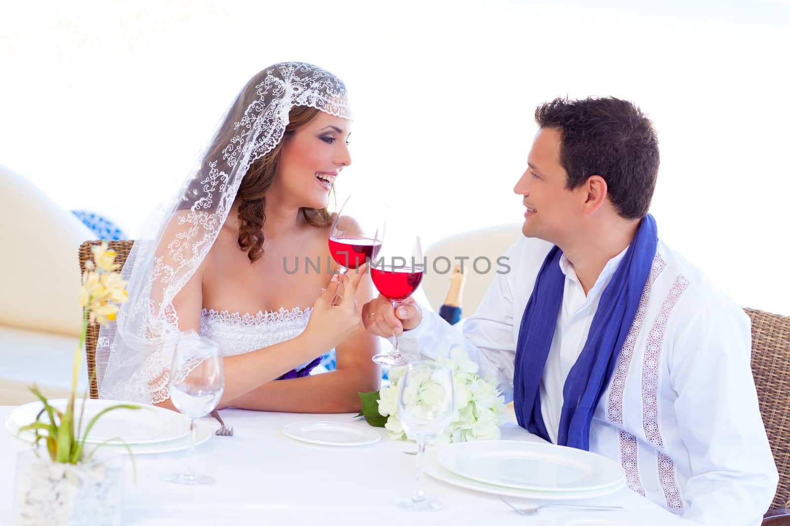 Couple in wedding day cheering with red wine in banquet table