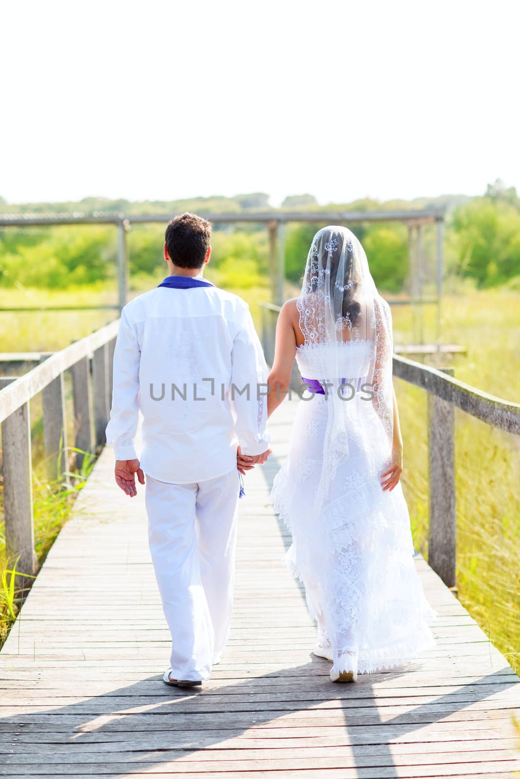 Couple happy in wedding day walking in outdoor rear view