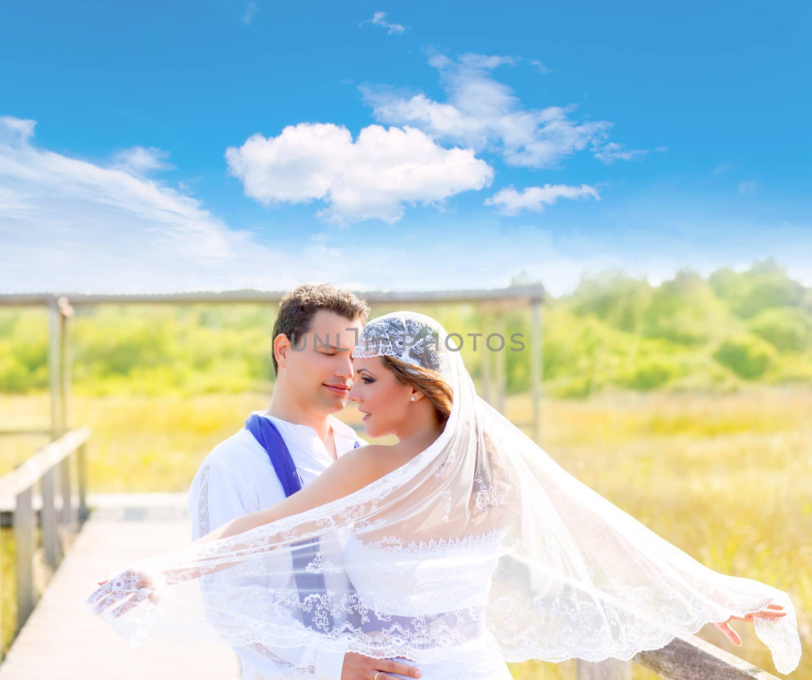 Couple in wedding day outdoor with wind on veil