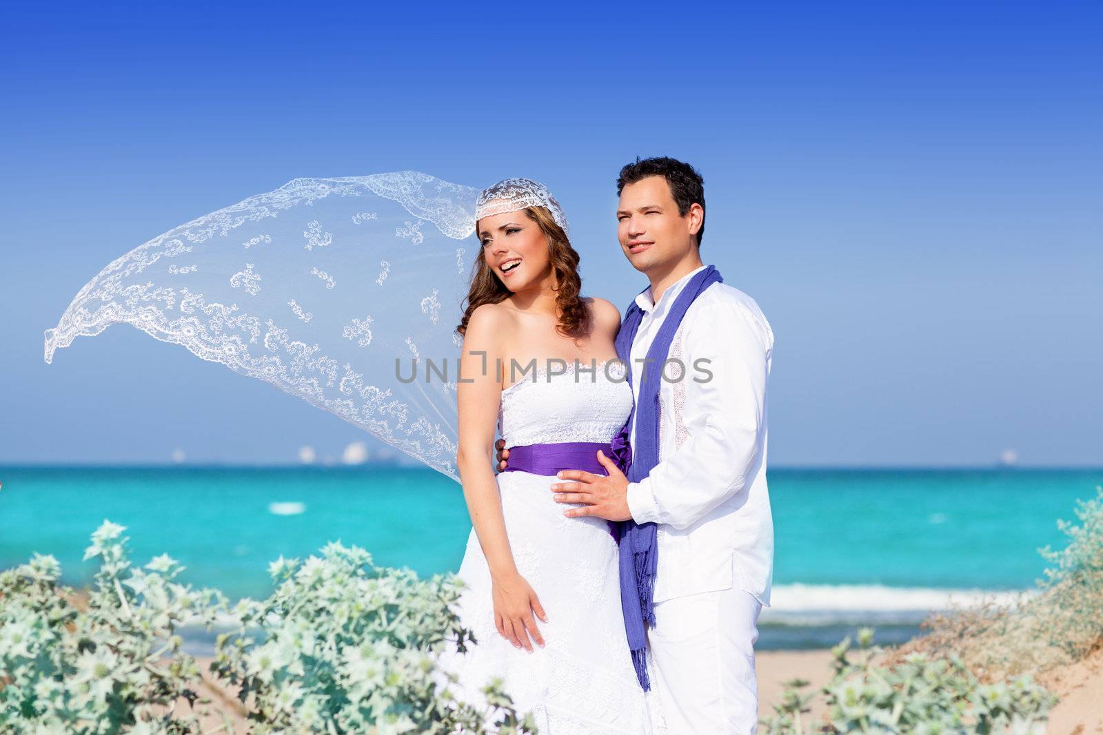 Couple in wedding day on beach sea with wind on veil