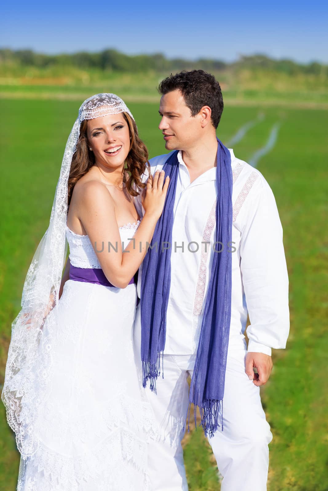 Couple in wedding day hug in outdoor green meadow