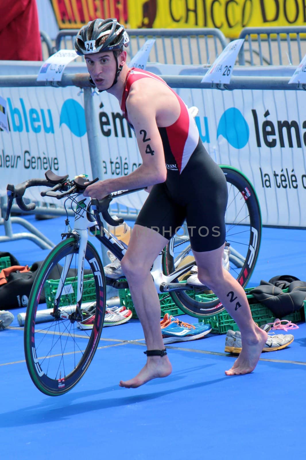 GENEVA, SWITZERLAND - JULY 22 : unidentified athlet holding his bike at transition space at the International Geneva Triathlon, on July 22, 2012 in Geneva, Switzerland.