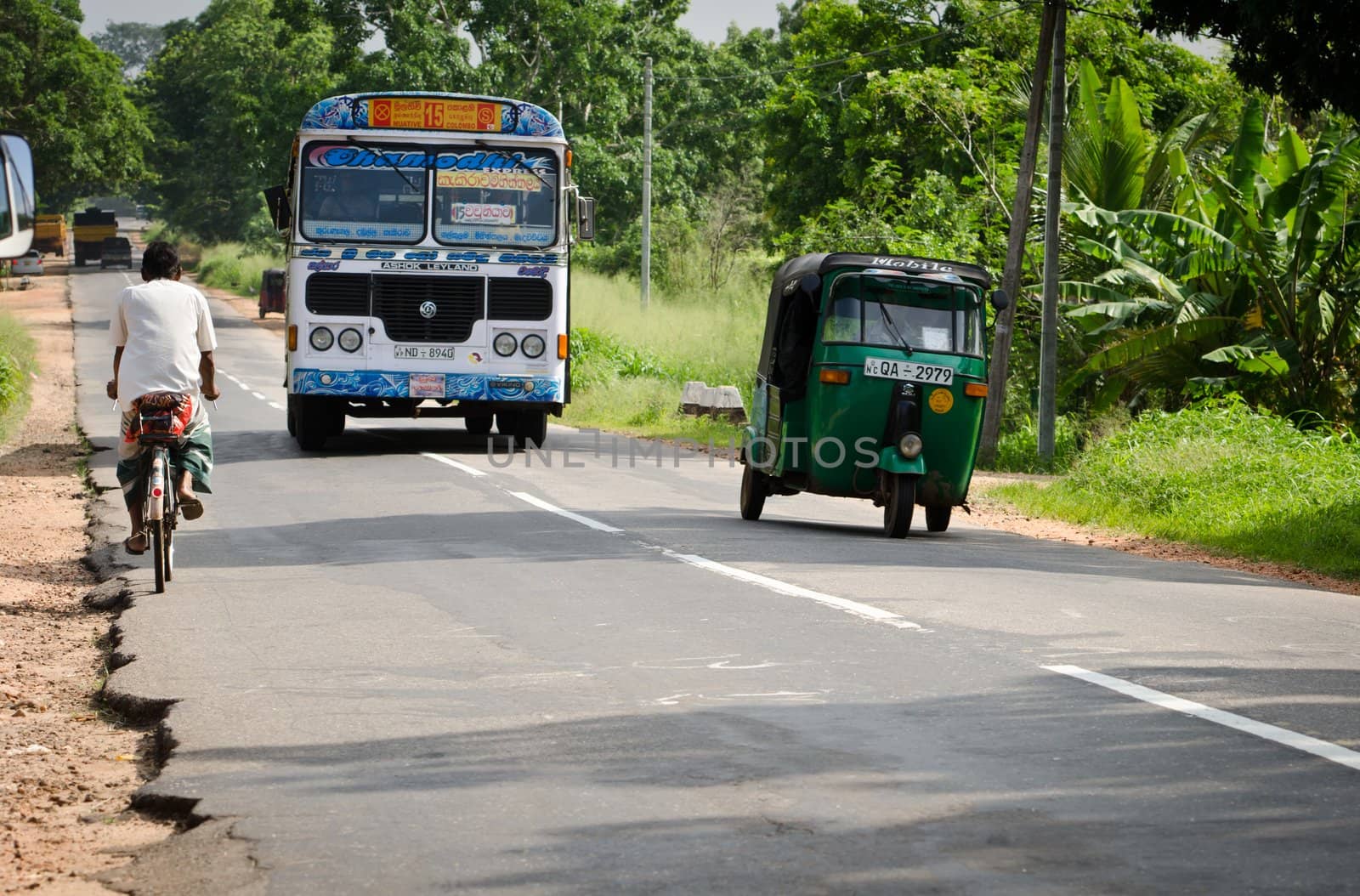 Habarana, Sri Lanka - December 6, 2011: Regular public bus from Muative to Colombo, bicycle and tuk-tuk ob narrow road. There are the most popular public transport type in Sri Lanka.