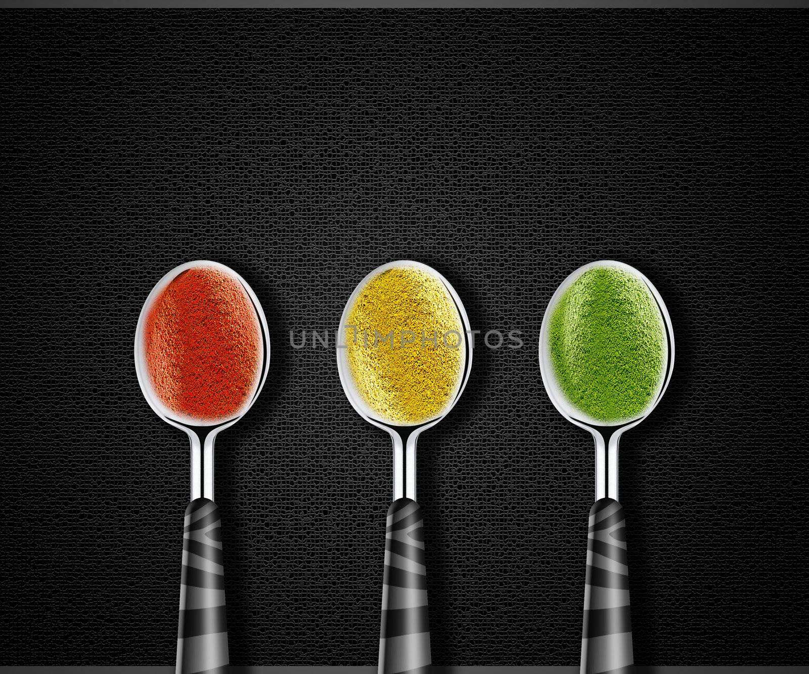 Collection of green, yellow and red spices on spoons onblack background