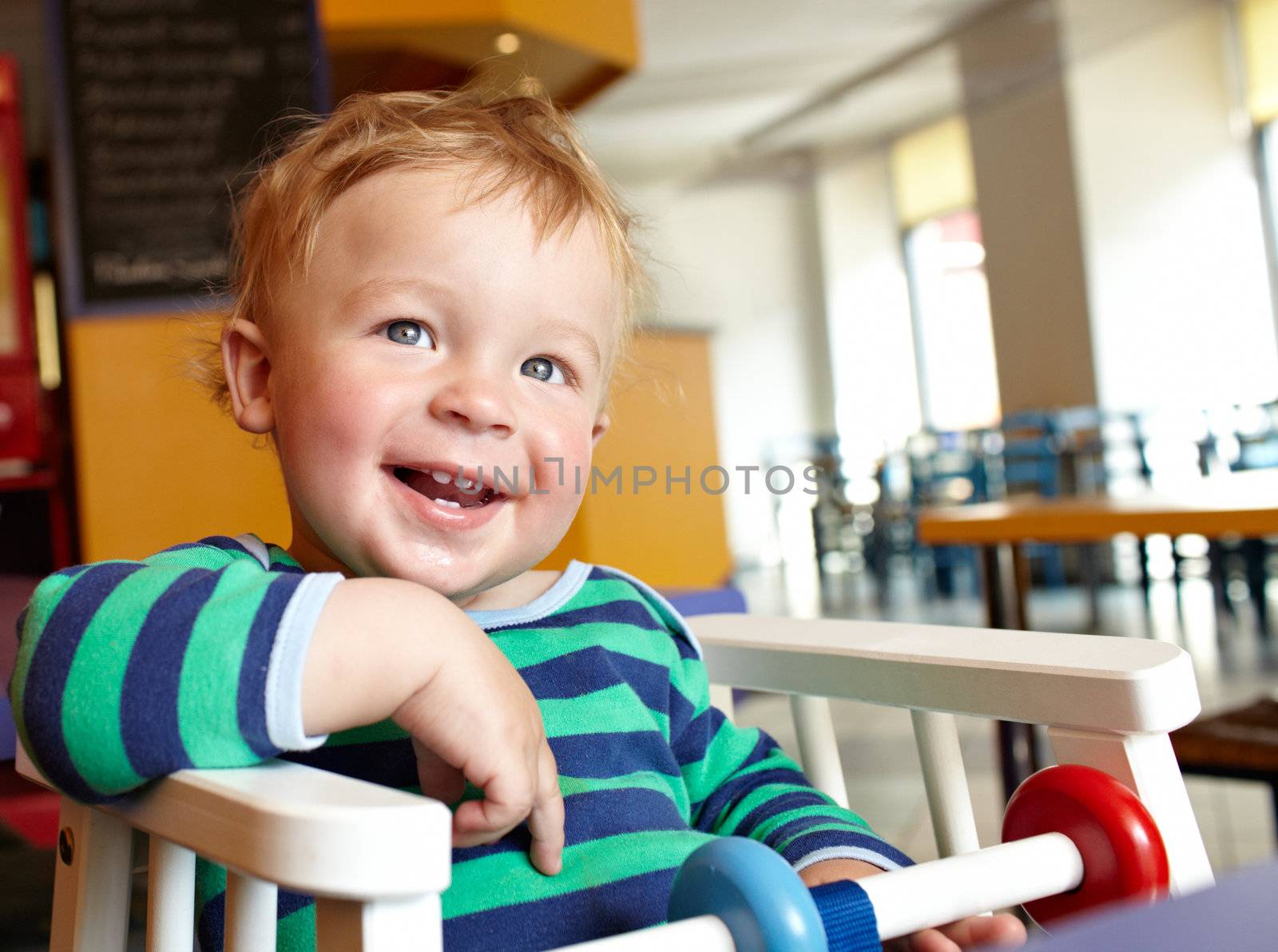 Cute boy having delicious lunch in restaurant and laughing. Natural bright colors.