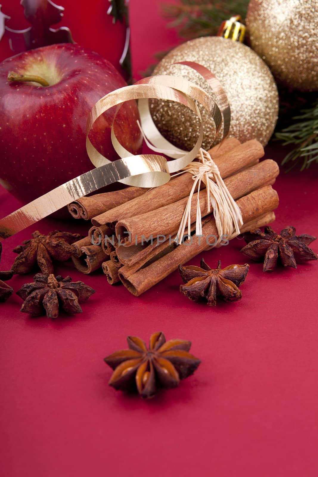 christmas decoration aromatic red apple, cinnamon, anise and tree on red background