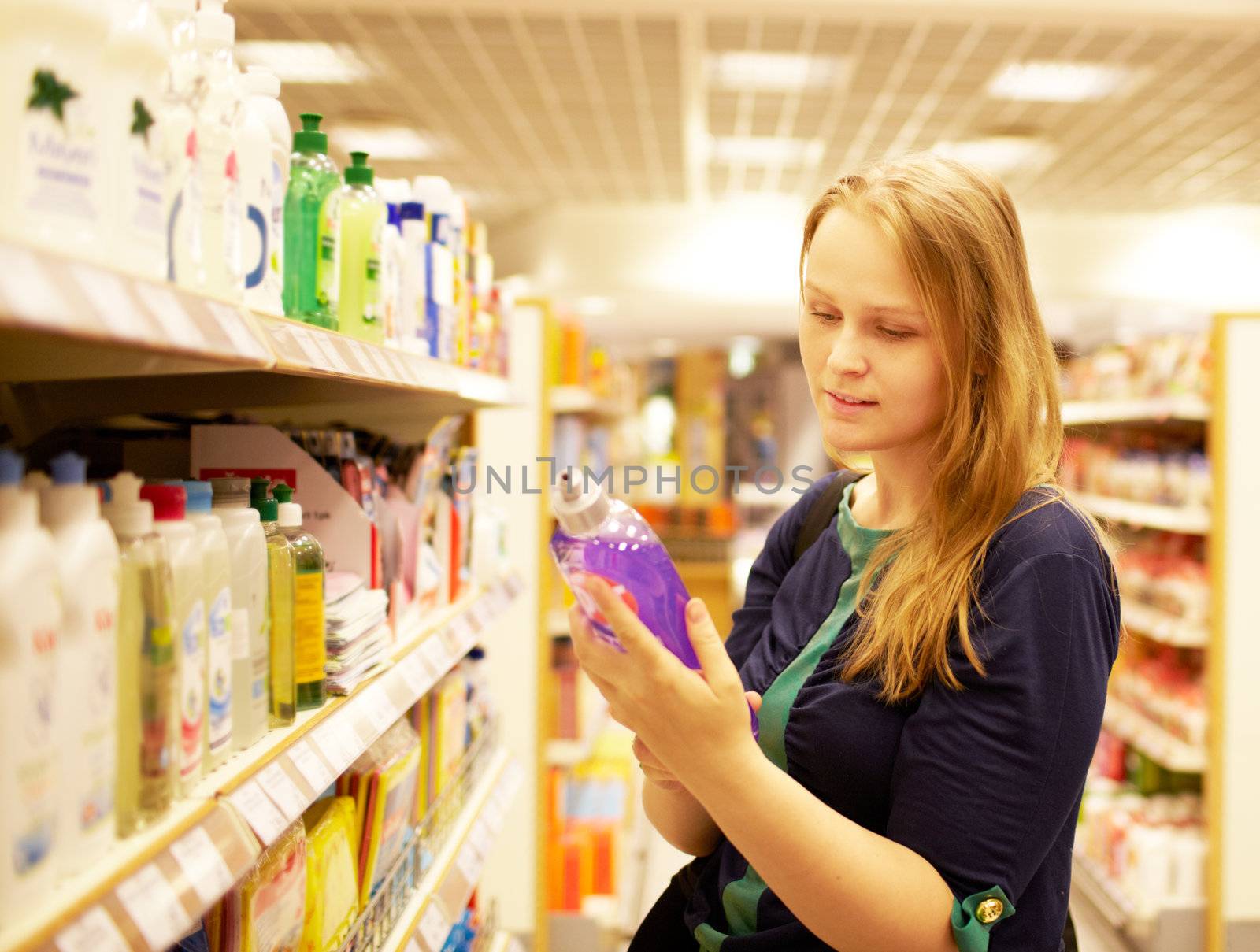 Young woman in the supermarket reading inscription by danr13