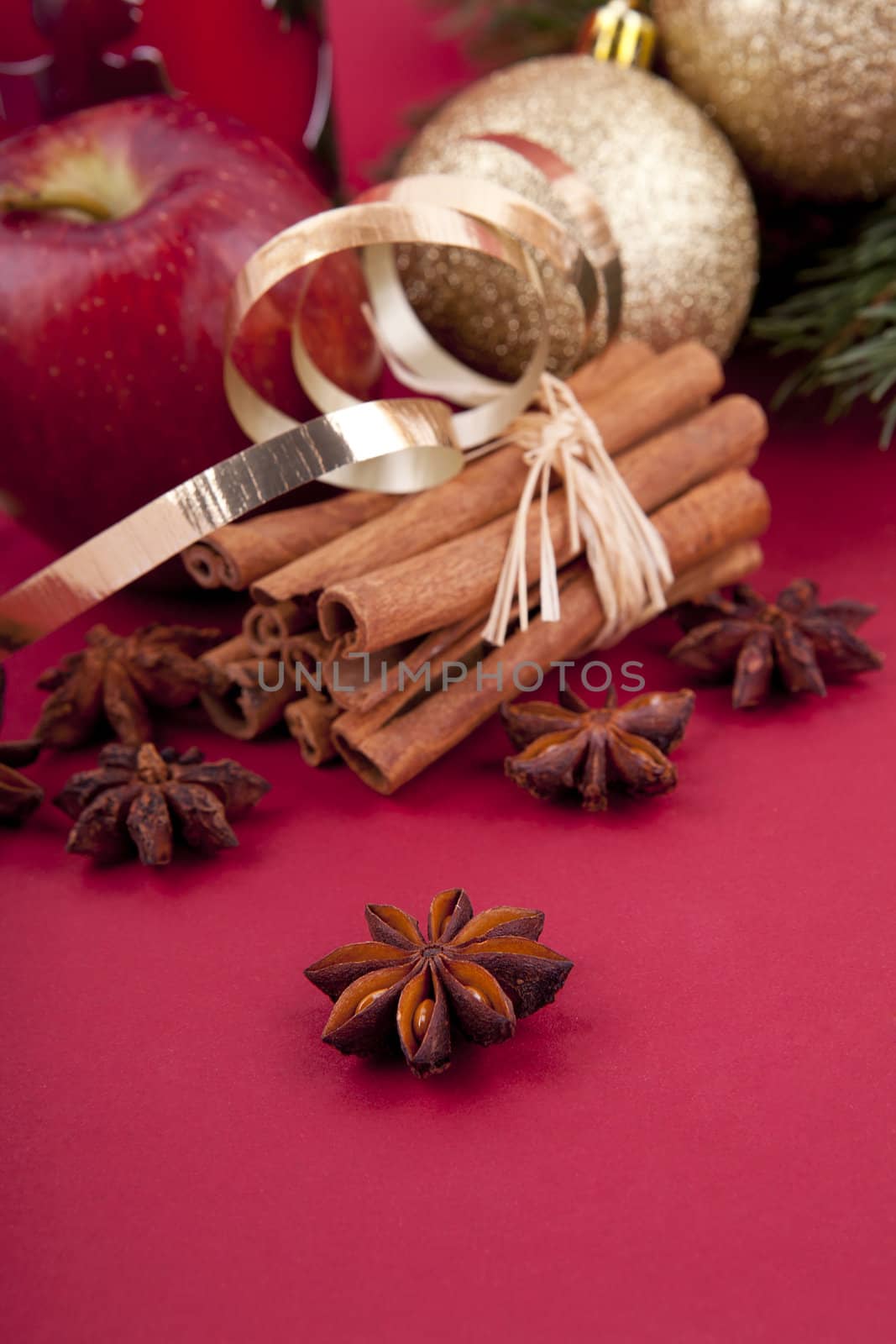 christmas decoration aromatic red apple, cinnamon, anise and tree on red background