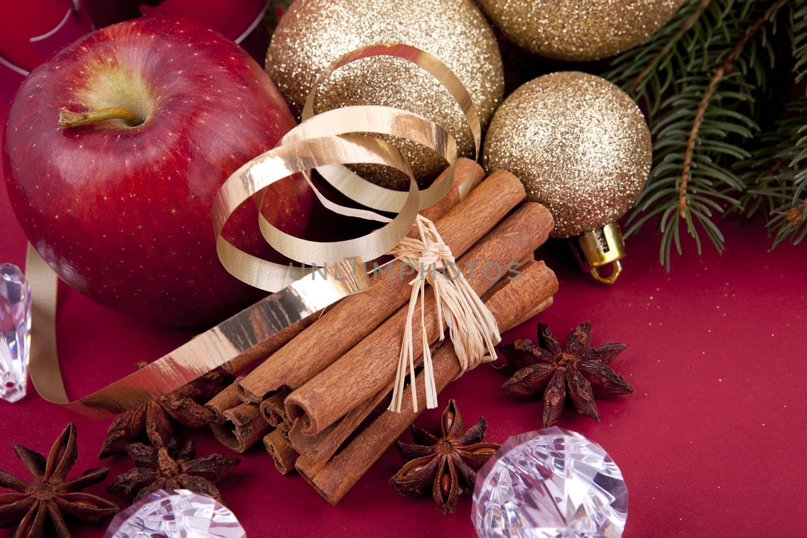 christmas decoration aromatic red apple, cinnamon, anise and tree on red background