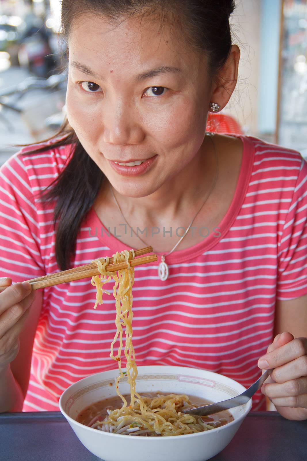 Asian lady is eating noodle soup