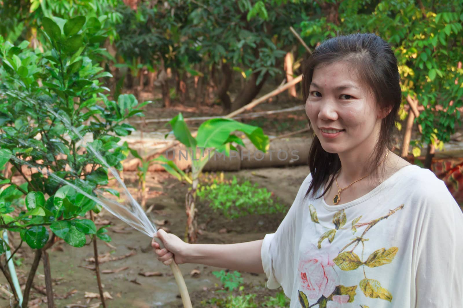 Asian woman watering the plants in backyard.