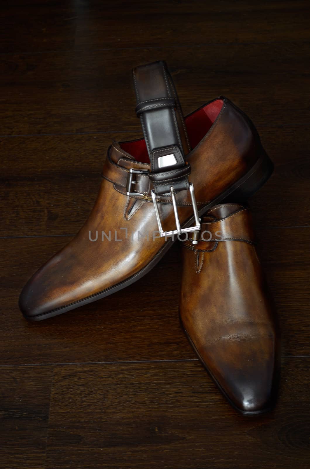Luxury italian style brown leather shoes and belt for him against a dark background.