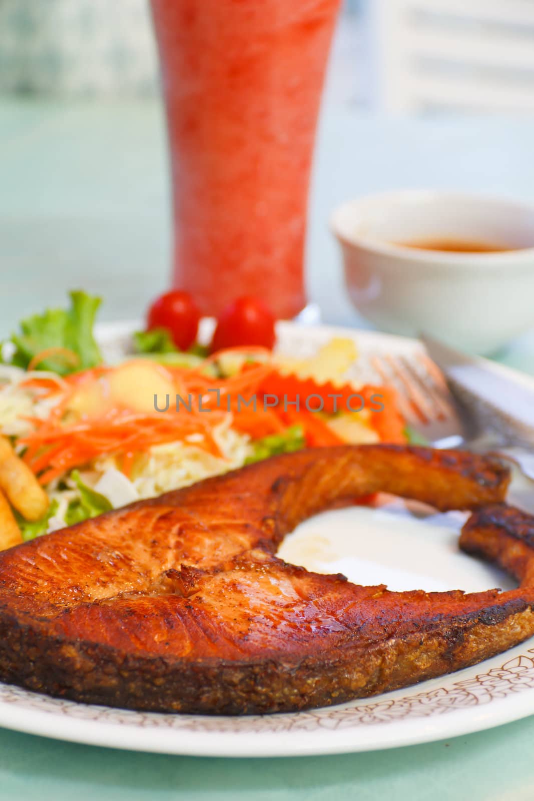 Crispy grilled salmon steak with cherry tomatoes and salad
