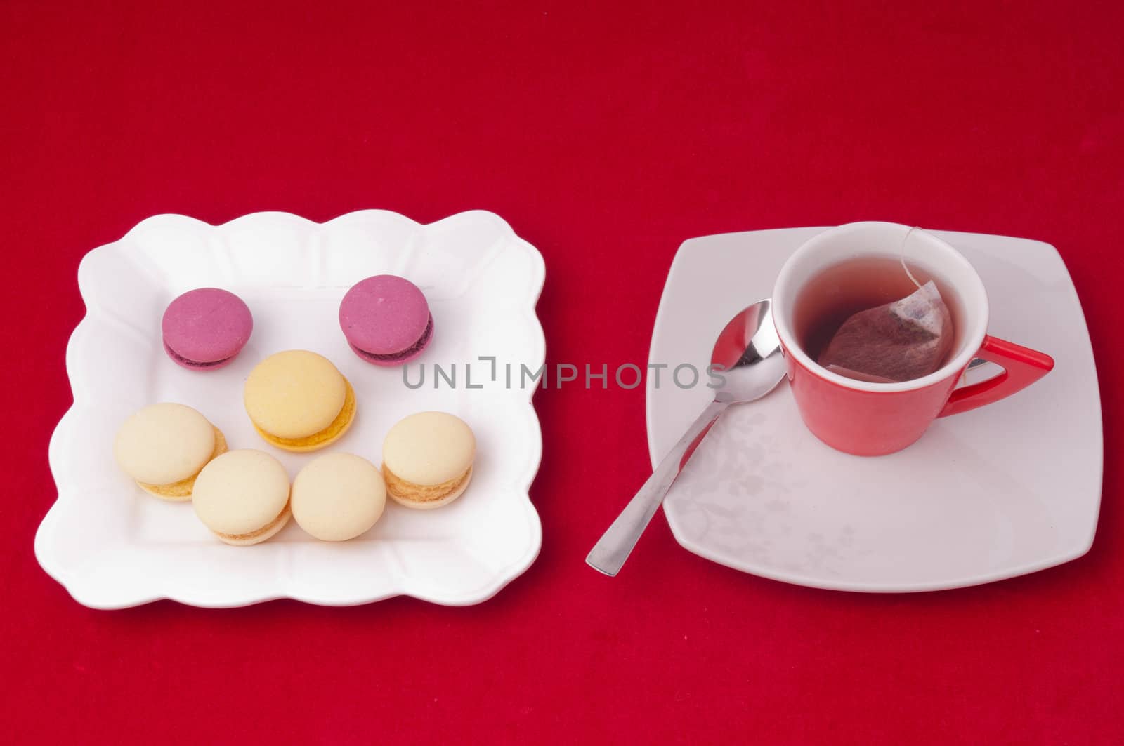 Cup of tea and smile of macaroons on velvet tablecloth by bigmagic