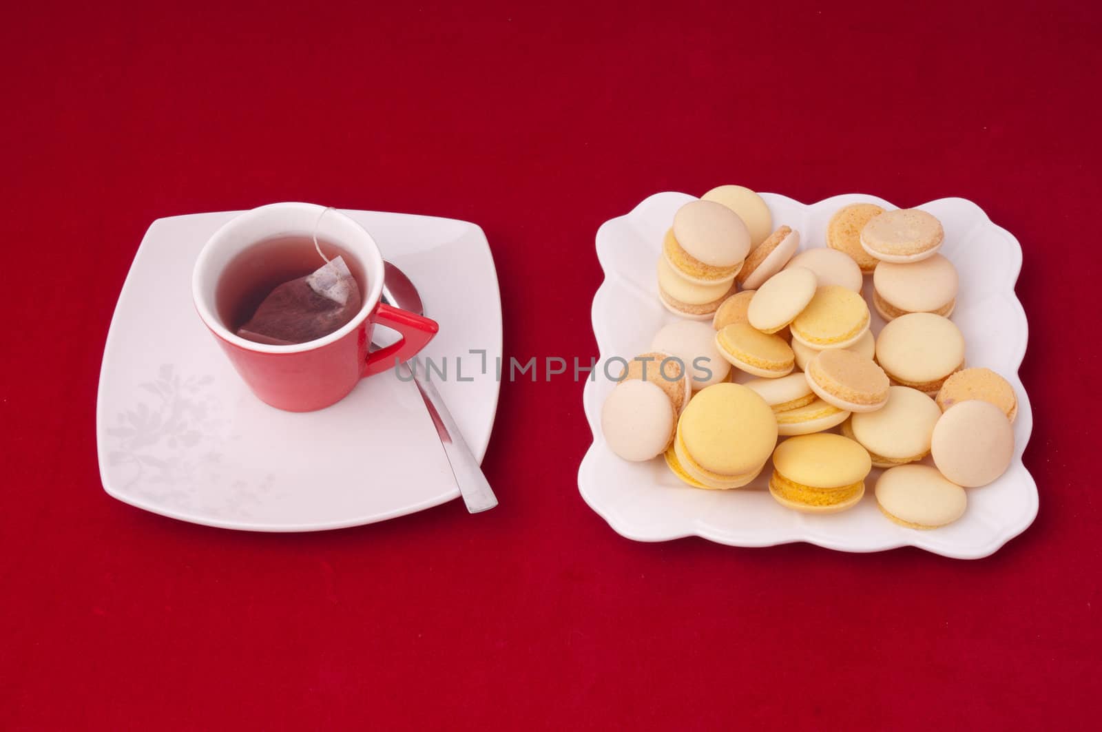 Cup of tea and plate of mixed macaroons on a velvet tablecloth