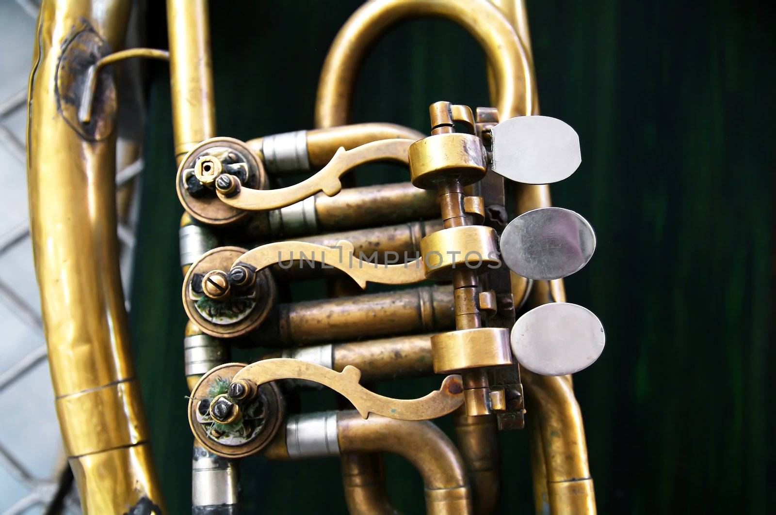 Old brass instrument  with three valves hanging on the wall