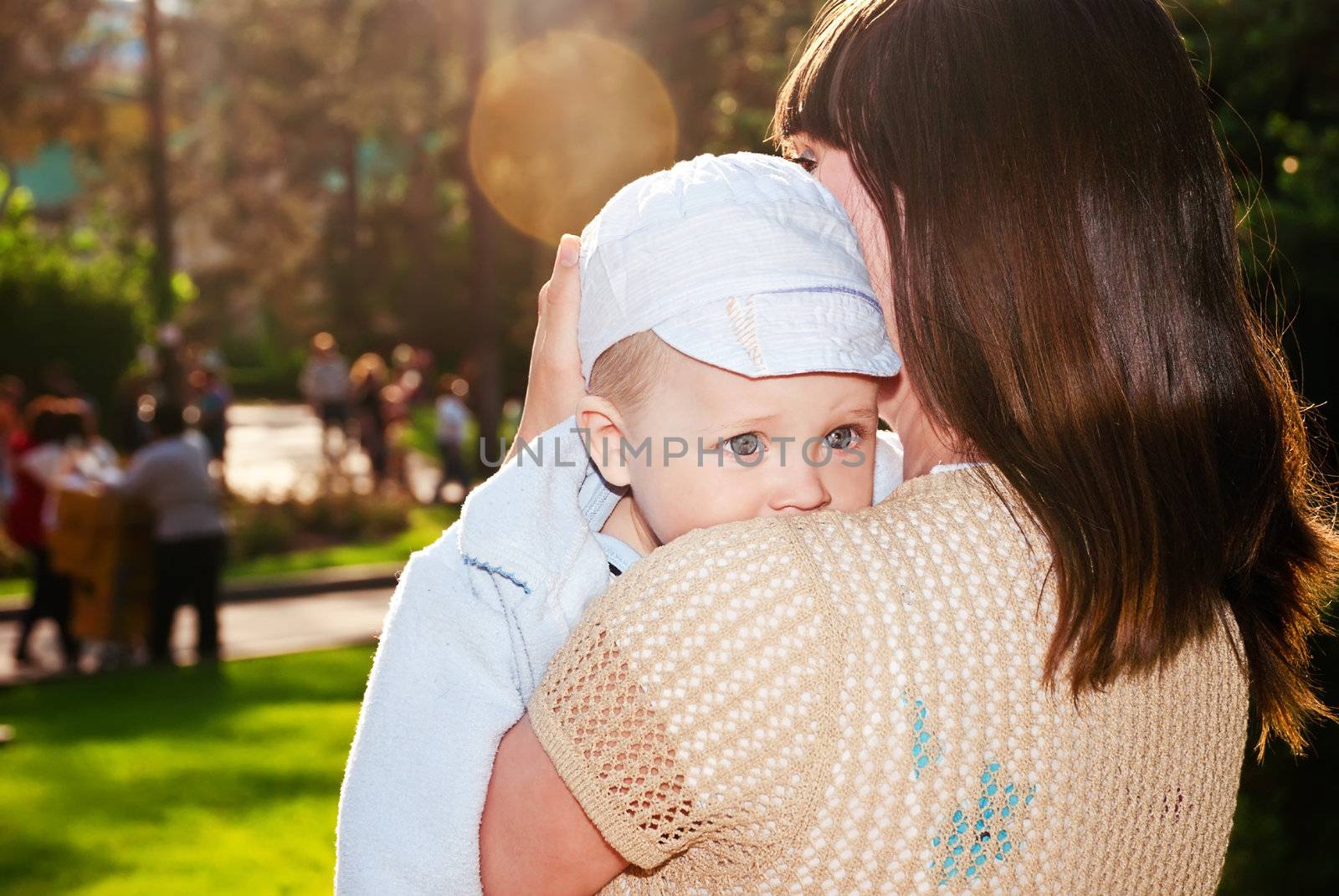 Gorgeous baby looks over his shoulder, my mother in a sunny park.