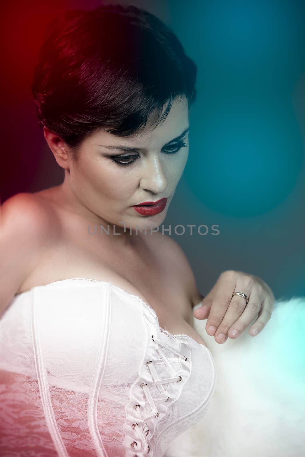 Beautiful sad bride with white corset, colorful lights