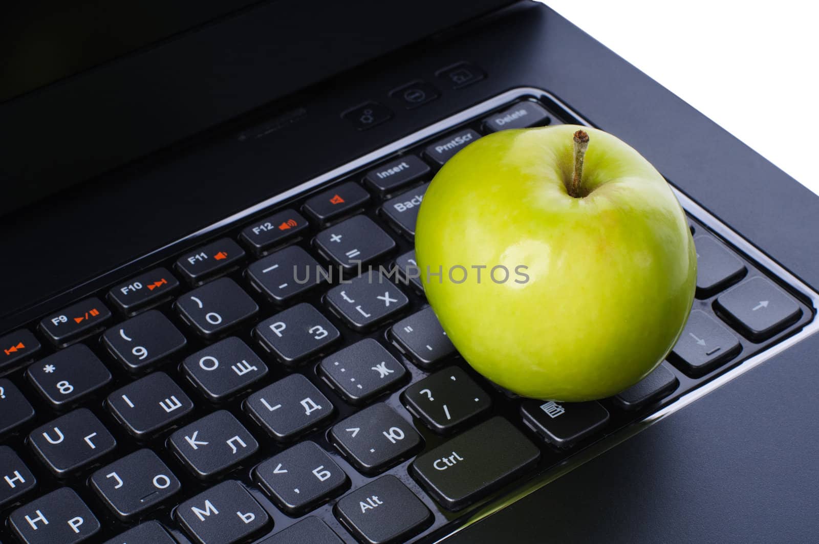 Green apple on laptop keyboard isolated on white background