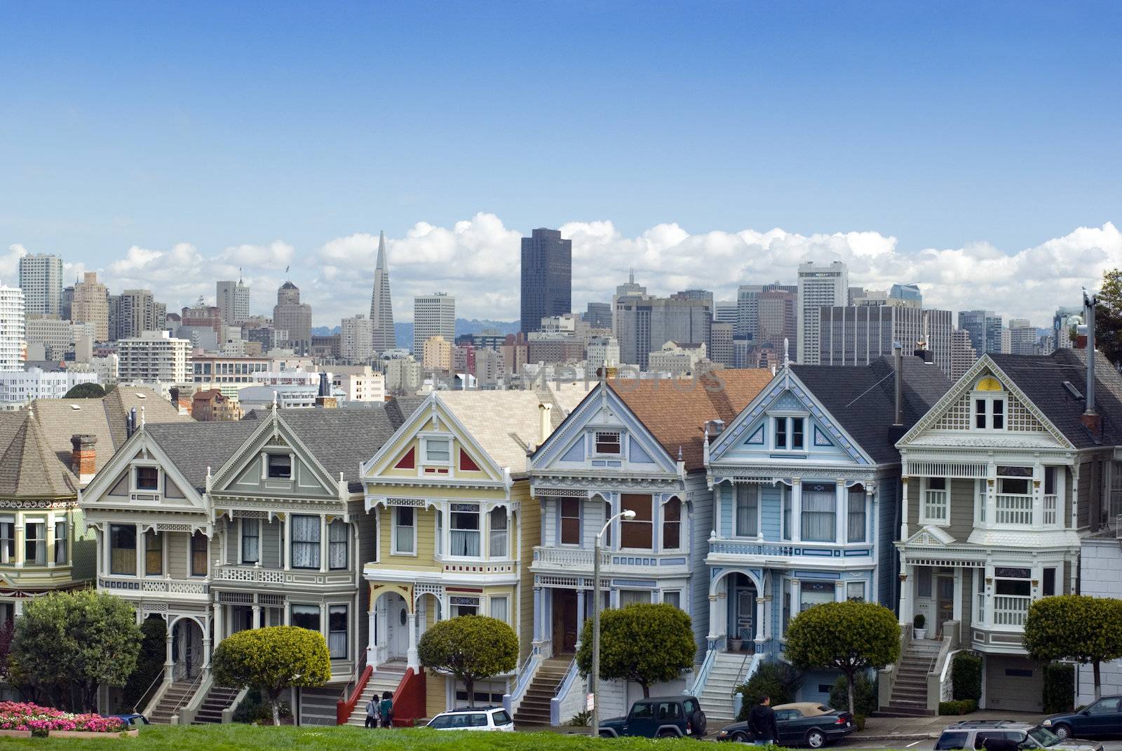 Historic and colourful victorian era houses at Alamo square with the San Francisco city skyline in the distance
