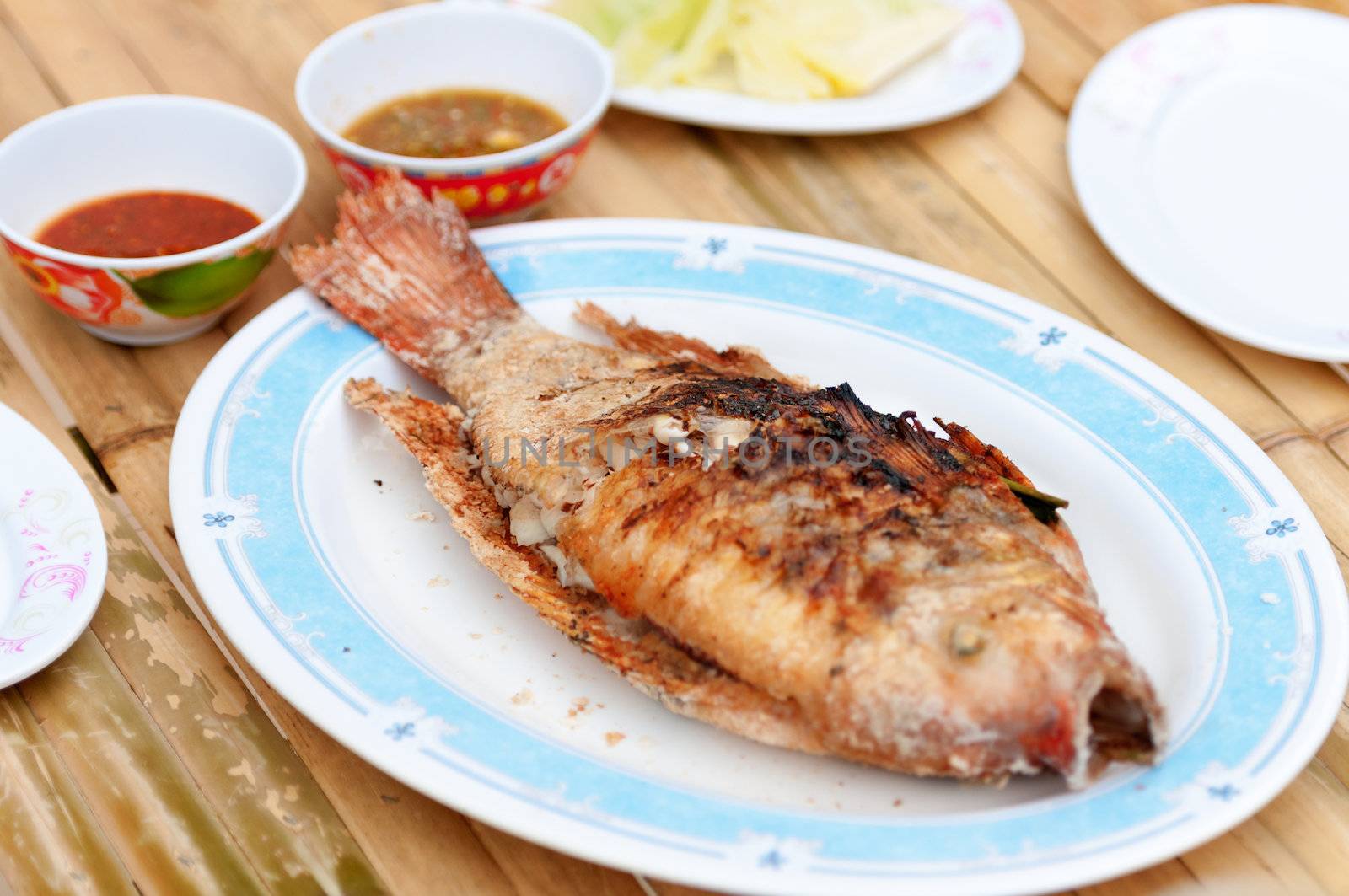 Two grilling sea fishes on plate with sauces. Shallow depth of field, focus on fish middle.