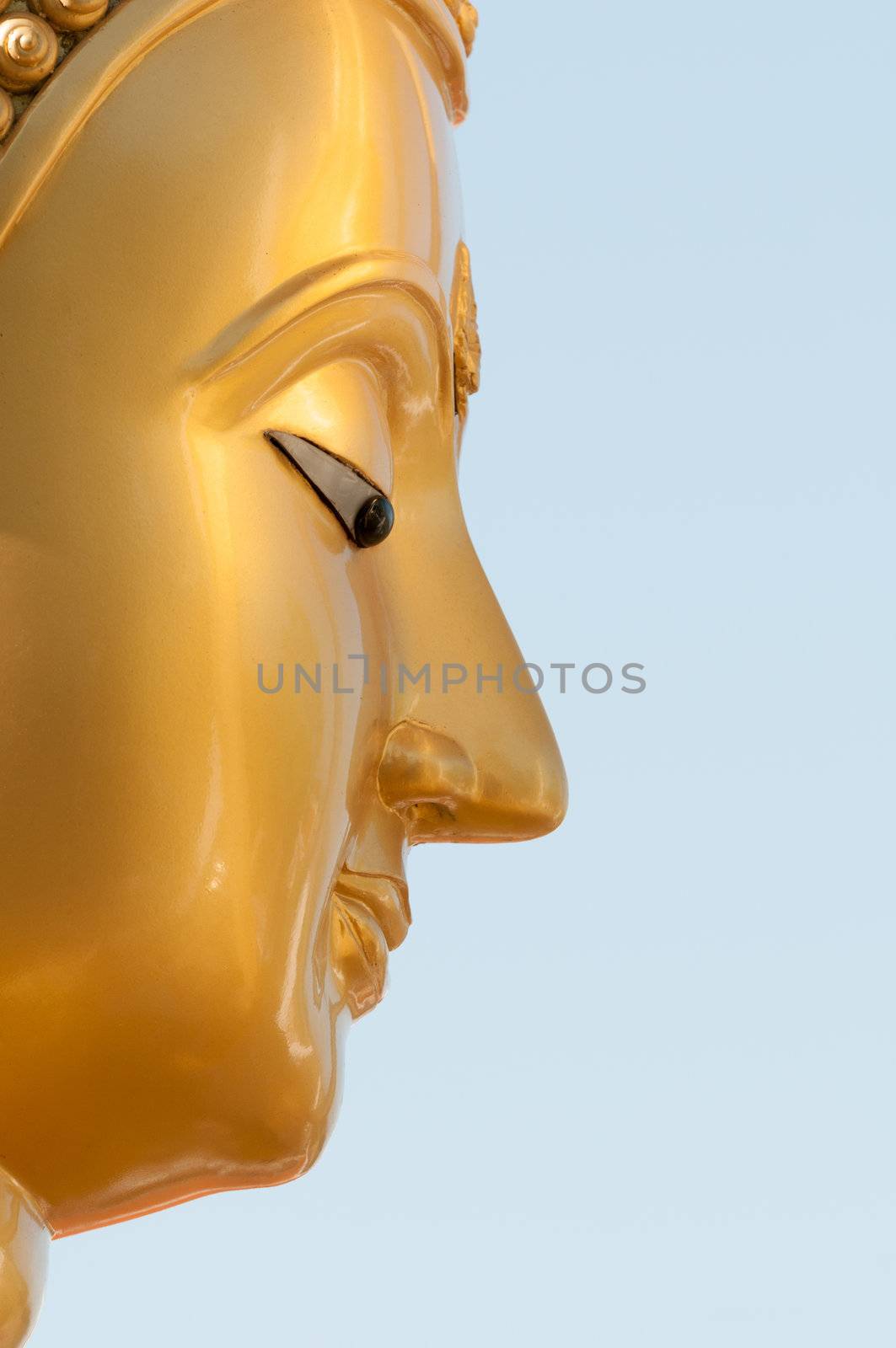 Buddha face in profile with blue clean sky on background