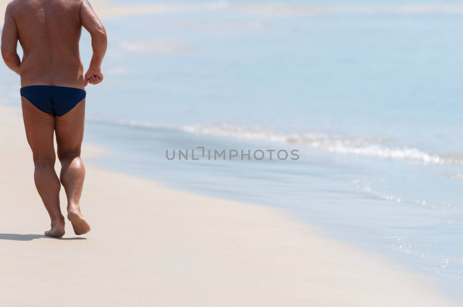 Running bare legs of male runner jogging on beach.