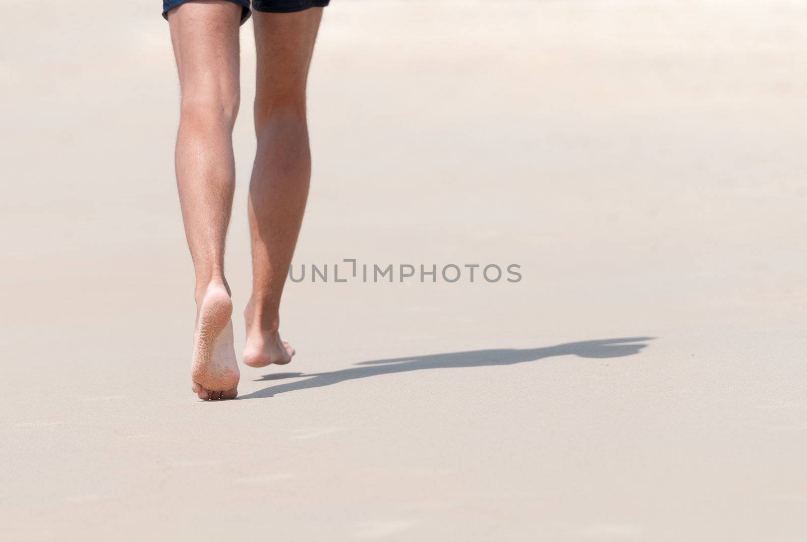 Running bare legs of runner jogging on beach. Shallow depth of field, focus on left foot.